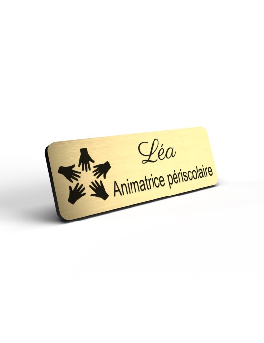 Badge personnalisé animatrice périscolaire, motif animation et activités pour enfants, détail de la finition or brossé