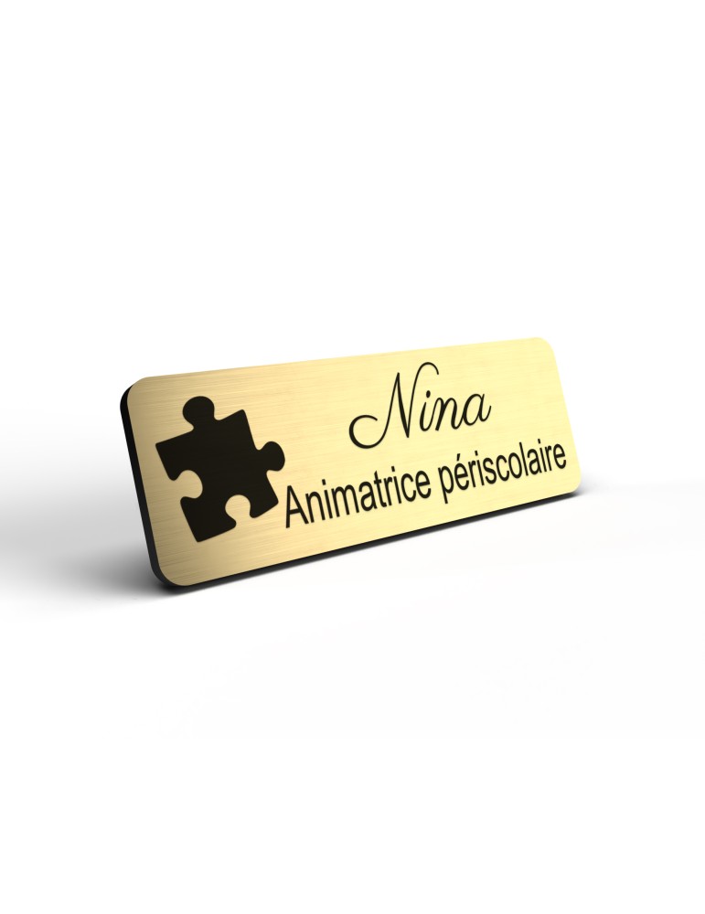 Badge personnalisé animatrice périscolaire, motif animation et activités pour enfants, détail de la finition or brossé
