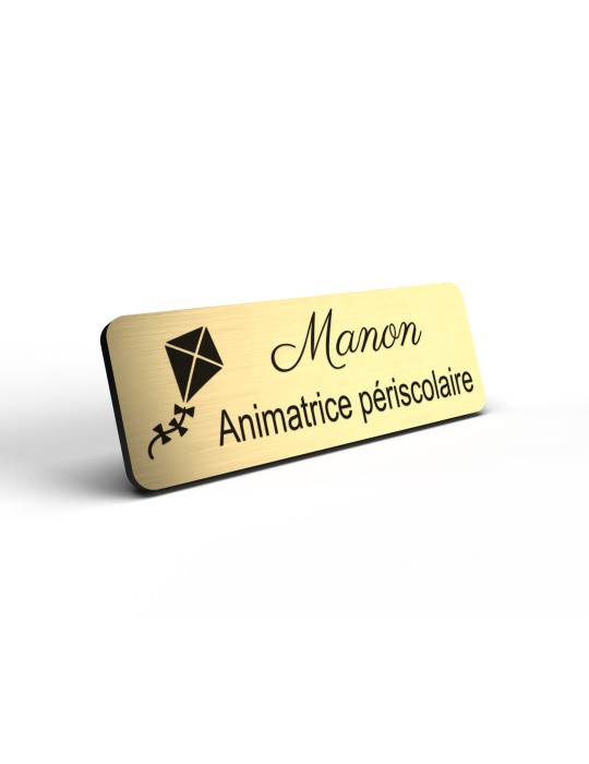 Badge personnalisé animatrice périscolaire, motif animation et activités pour enfants, détail de la finition or brossé
