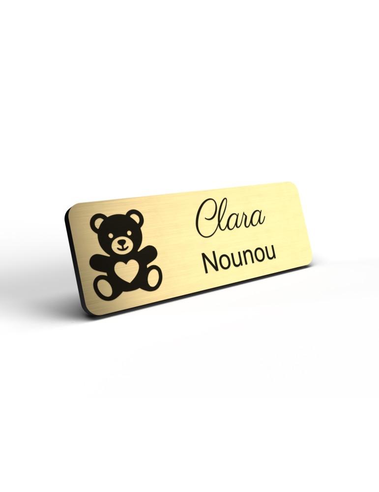 Badge personnalisé nounou, motif enfance et garde à domicile, détail de la finition or brossé